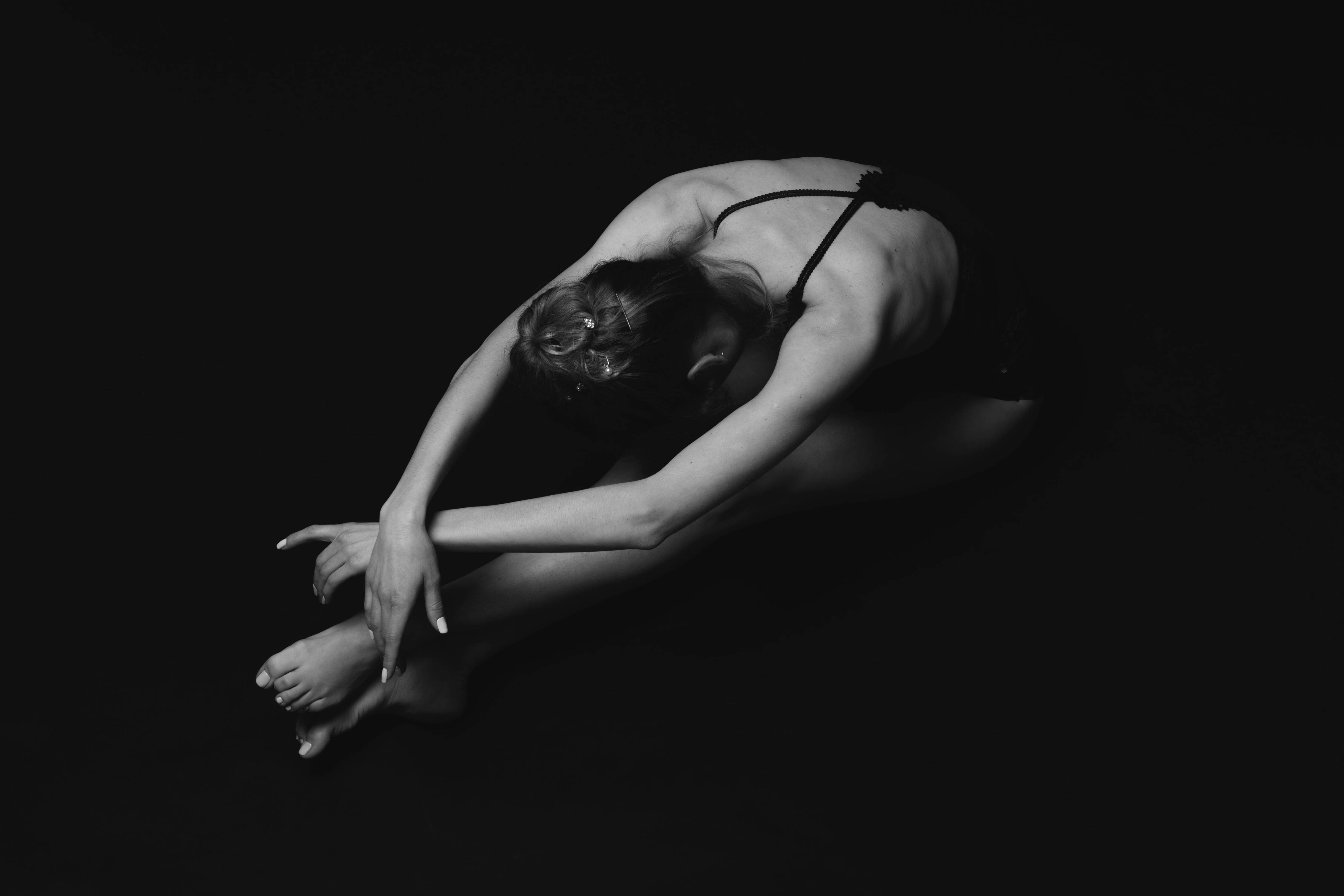 a ballet dancer sitting in a pose, dark background