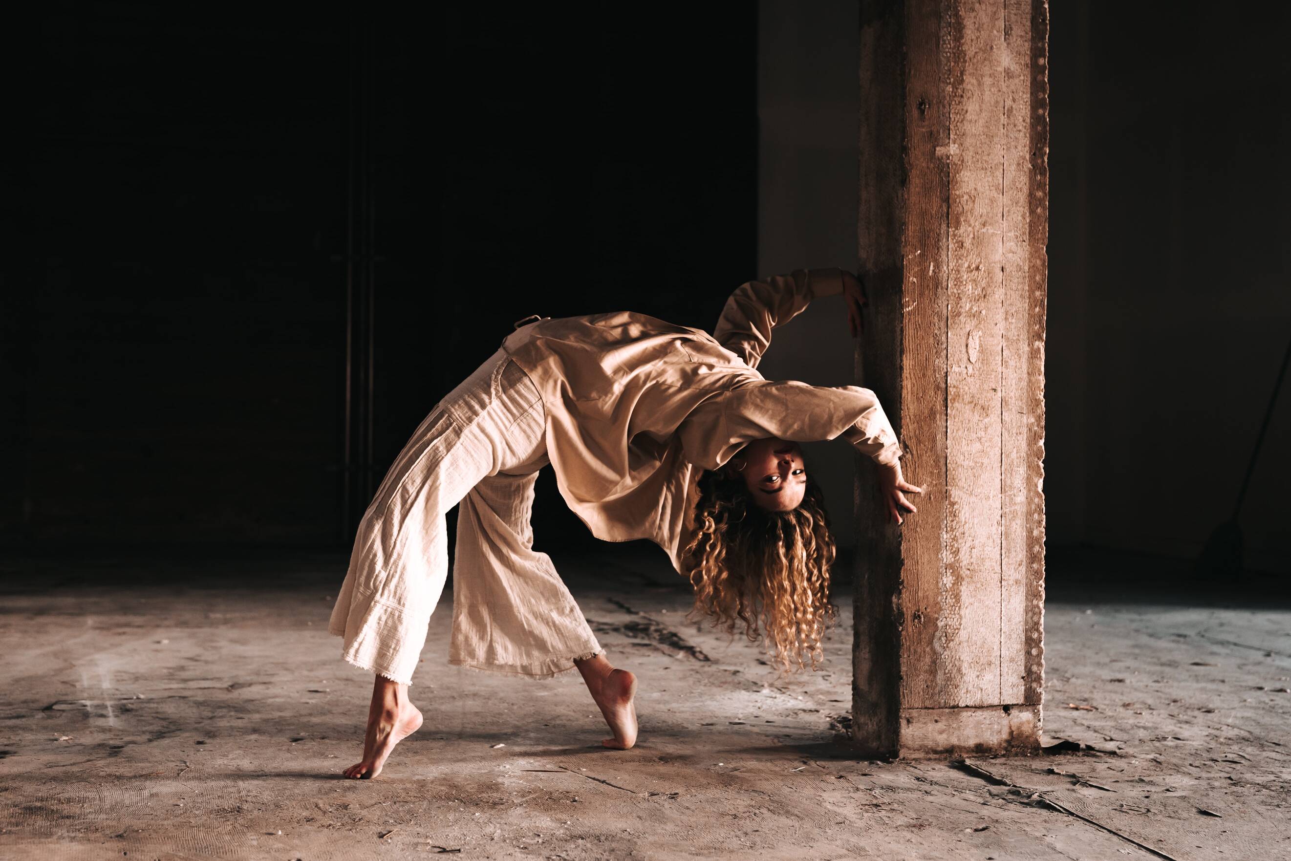 a dancer in a pose, beige colors, black background